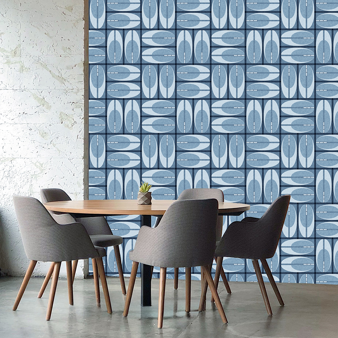 The artwork features a repeating geometric pattern of symmetrical shapes resembling elongated, curved diamonds or petals in various shades of blue and green. Each shape is split vertically with one half filled with a light blue and the other half filled with green or darker blue. The background is a light, almost pastel blue, which provides a soft yet vibrant backdrop. One of the blue shapes near the upper left contains a white starburst element, adding a focal point of brightness to the composition. The overall design conveys a modern, mid-century aesthetic with clean lines and harmonious color contrasts.